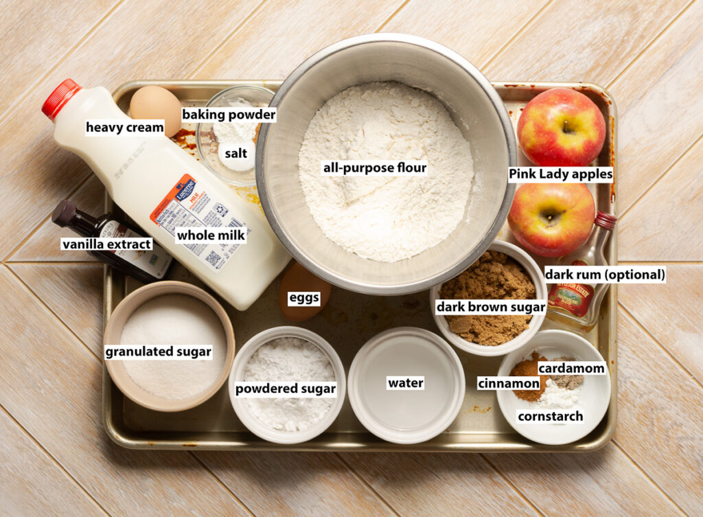 ingredients for apple pie funnel cakes - all-purpose flour, Pink Lady apples, dark brown sugar, dark rum, cinnamon, cardamom, cornstarch, water, eggs, granulated sugar, vanilla extract, whole milk, salt, baking powder, powdered sugar, heavy cream