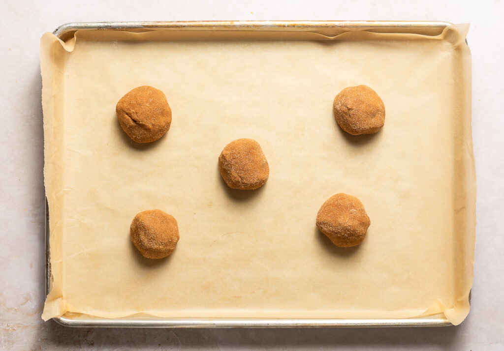 banana snickerdoodle cookie dough balls on a parchment lined baking sheet