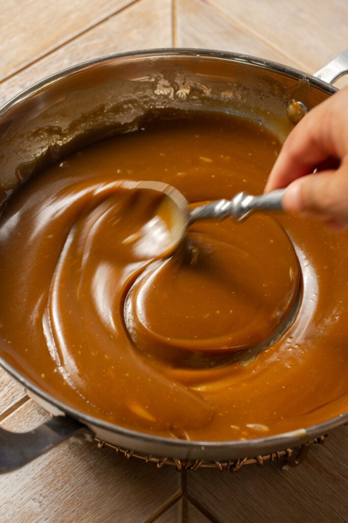 homemade butterscotch being stirred in a stainless steel pan