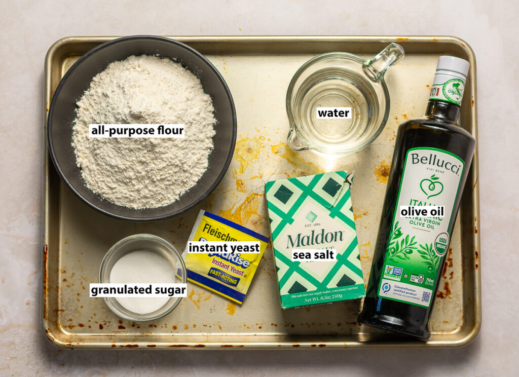 ingredients for homemade pizza dough - all-purpose flour, granulated sugar, instant yeast, sea salt, olive oil & water