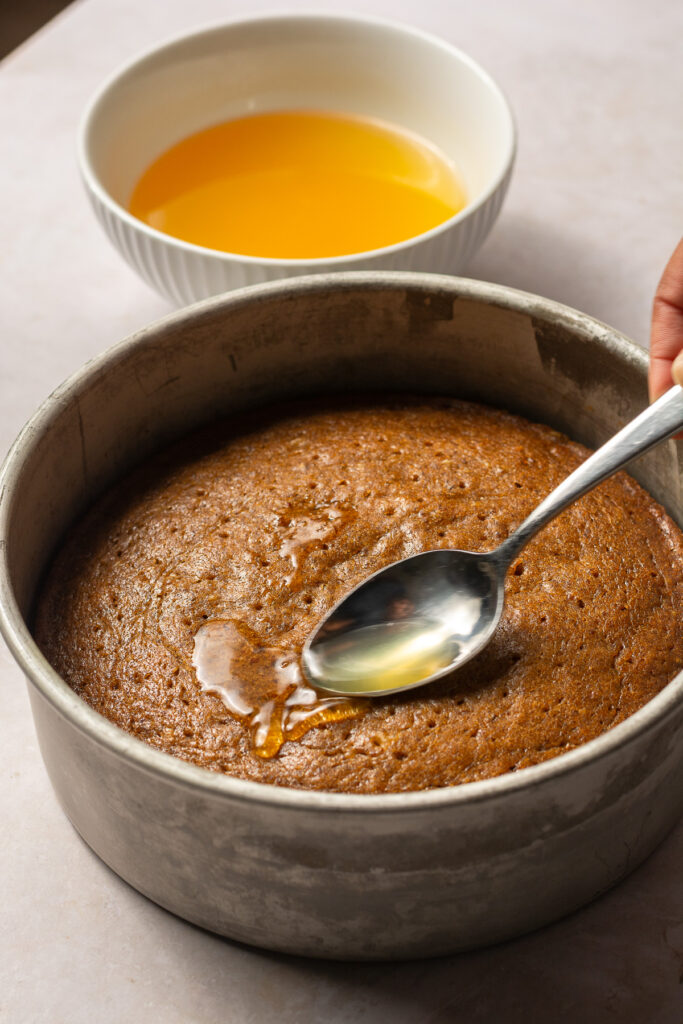 soaking hummingbird cake layers with pineapple-rum simple syrup