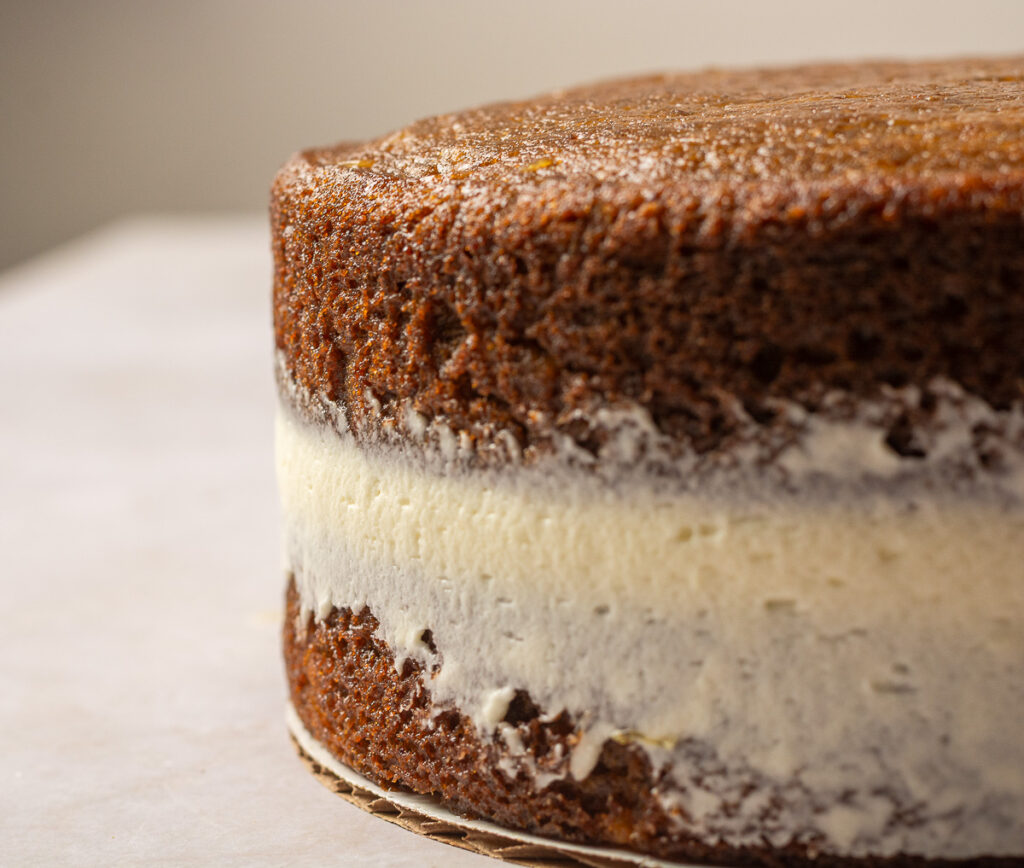 stacking a layer cake with cream cheese frosting