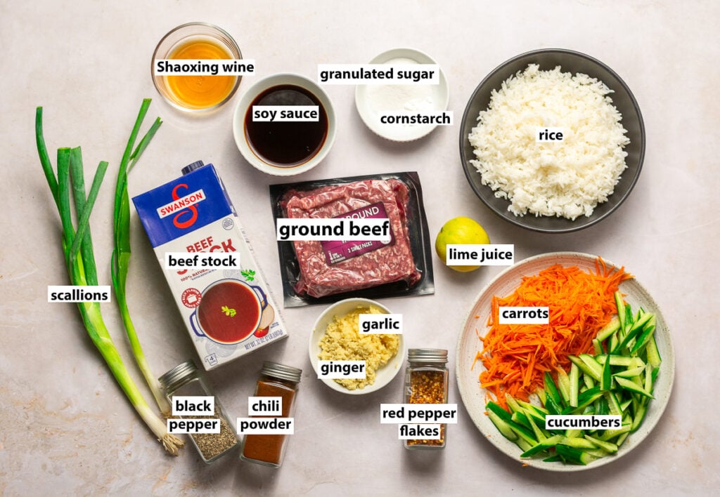 ingredients for soy ginger ground beef bowls - rice, carrots, cucumbers, ginger, garlic, ground beef, beef broth, soy sauce, granulated sugar, cornstarch, Shaoxing wine, scallions, black pepper, chili powder, red pepper flakes & lime juice