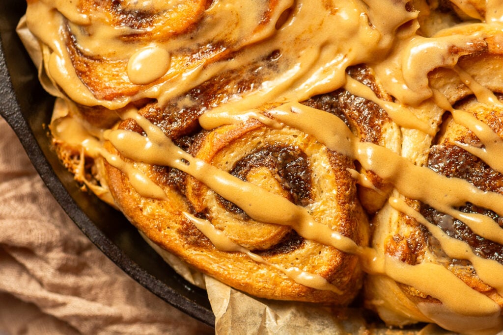 banana cinnamon rolls with brown sugar cream cheese frosting in a cast iron pan