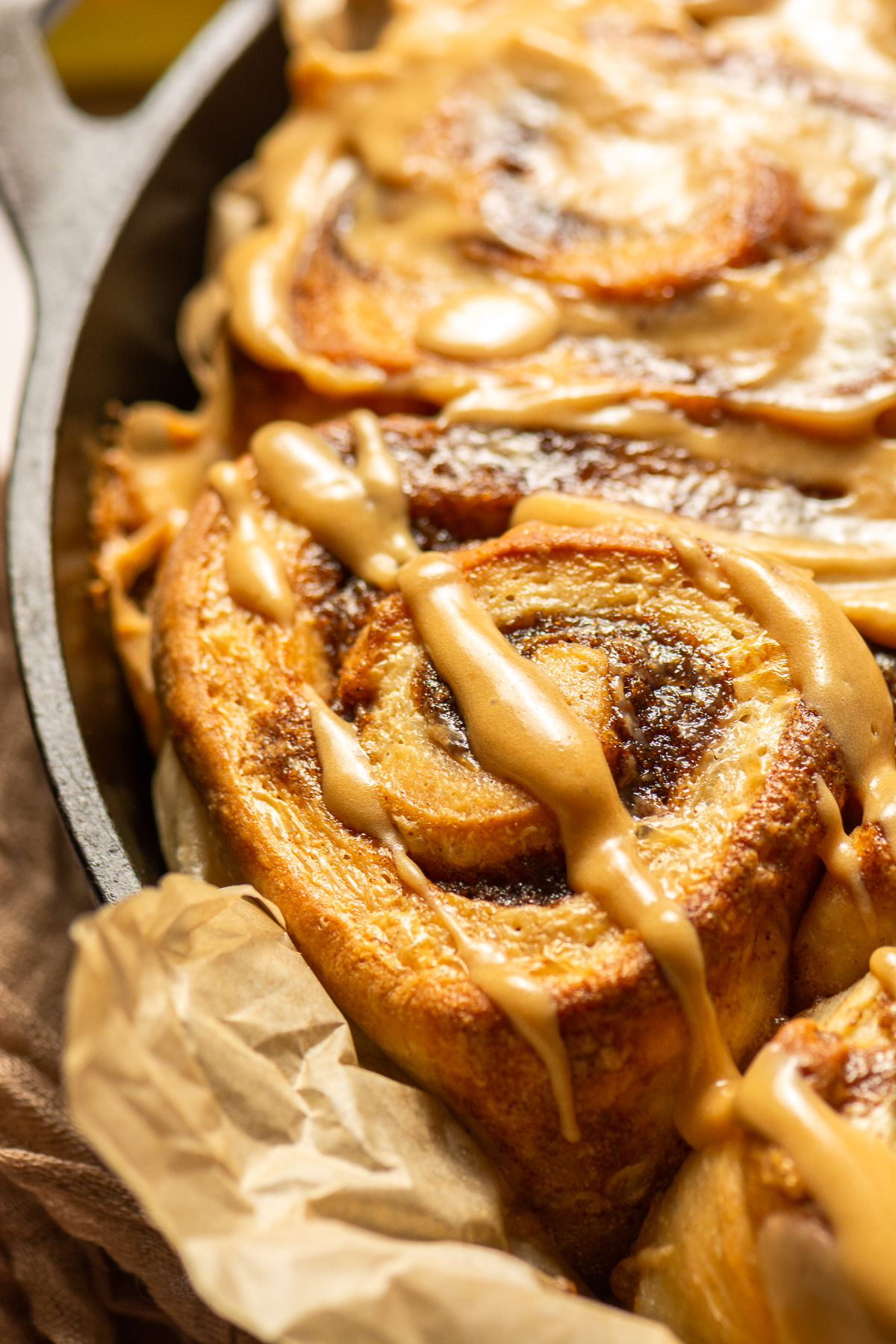 banana cinnamon rolls with brown sugar cream cheese frosting in a cast iron pan