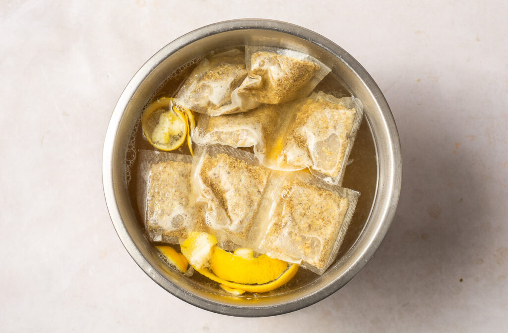 chamomile tea with lemon rind and chamomile tea bags in s stainless steel bowl