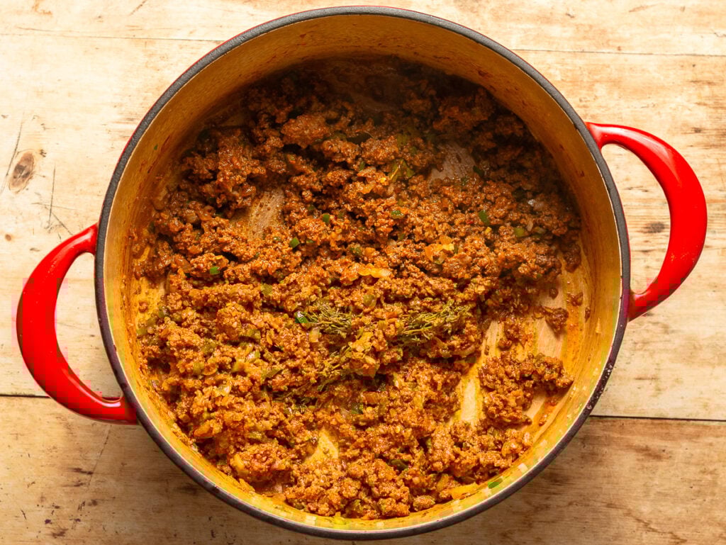 browning ground beef and Mexican chorizo with seasnonings in a dutch oven