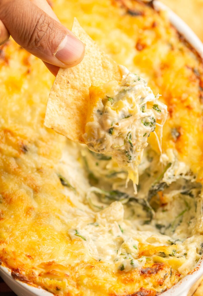 hot crab spinach dip scooped up with a tortilla chip