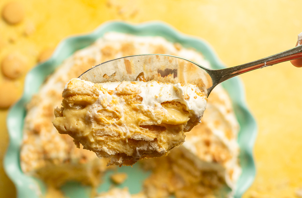 scoop of homemade banana pudding with whipped cream on a spoon.
