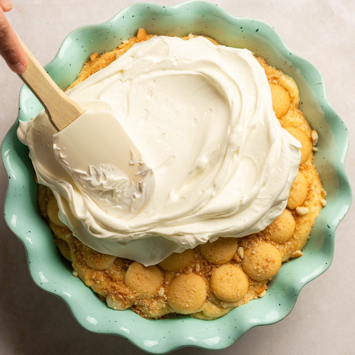topping homemade banana pudding with whipped cream.