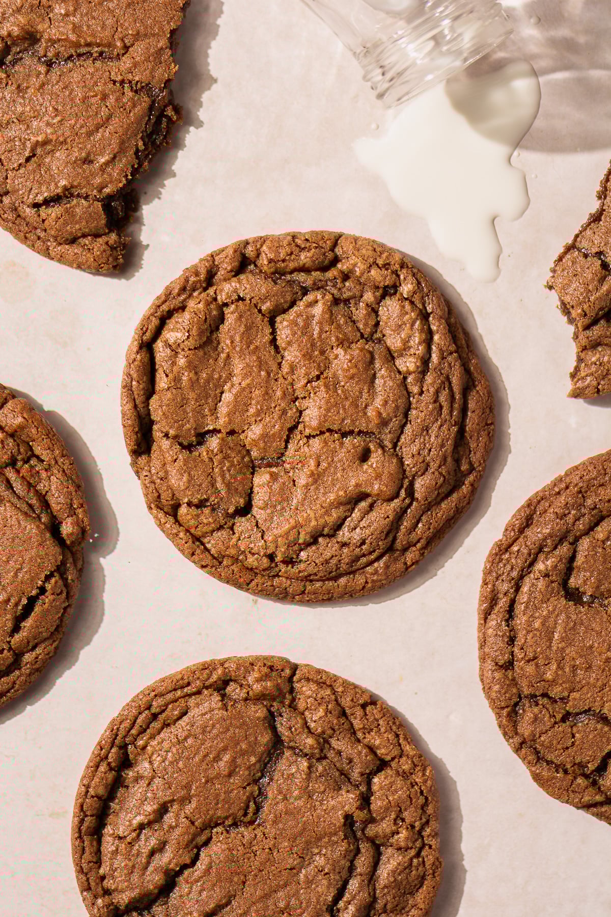 chocolate brownie cookies with spilled milk on counter.