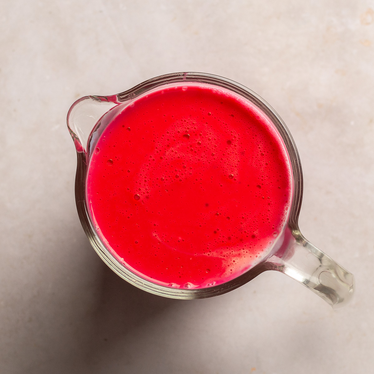 mixture of buttermilk, lemon juice and red food coloring in a glass measuring cup