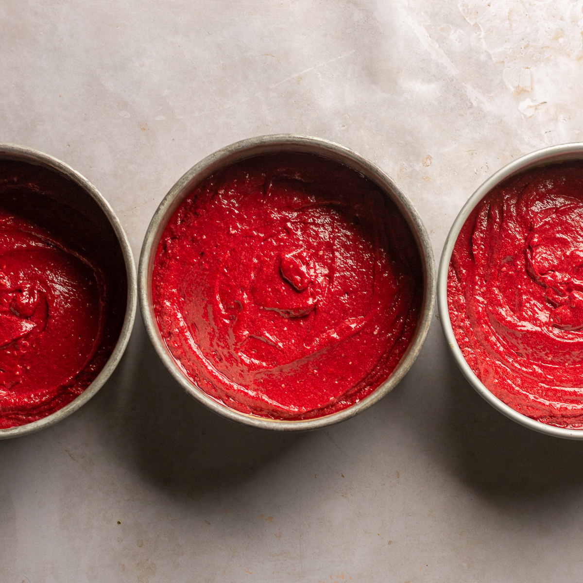 red velvet cake batter split in three 8-inch cake pans.