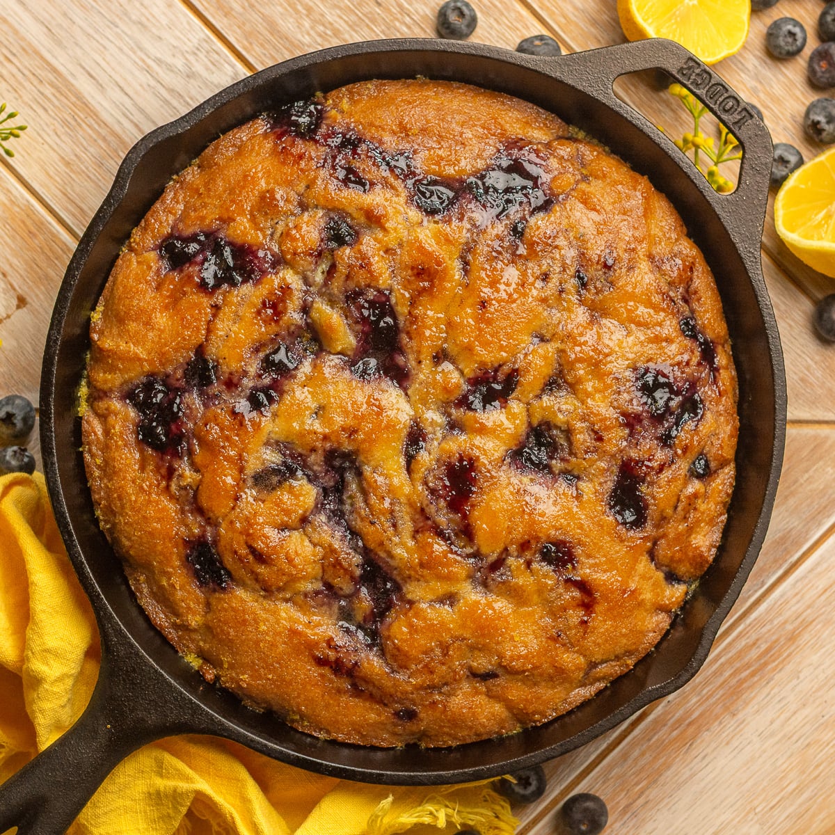 blueberry cornbread with honey lemon glaze in a cast iron skillet.