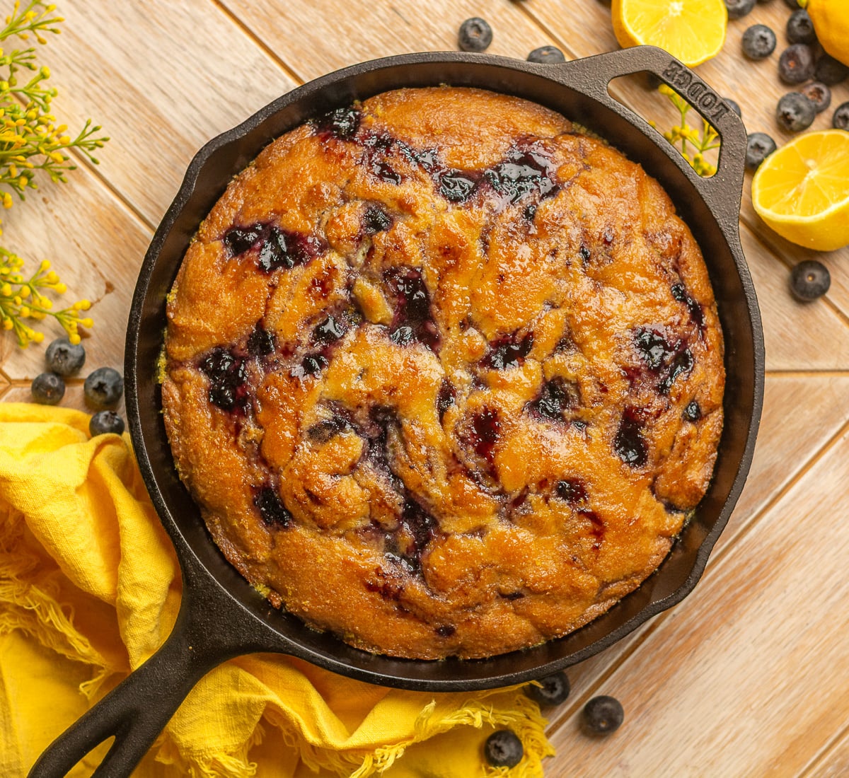 blueberry cornbread with honey lemon glaze in a skillet.
