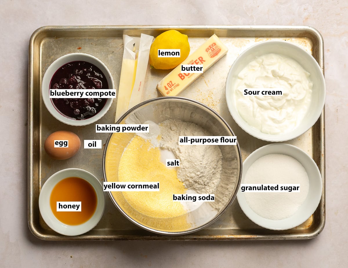 ingredients for blueberry cornbread - cornmeal, oil, egg, all-purpose flour, blueberry compote, lemon, butter, sour cream, sugar, honey.