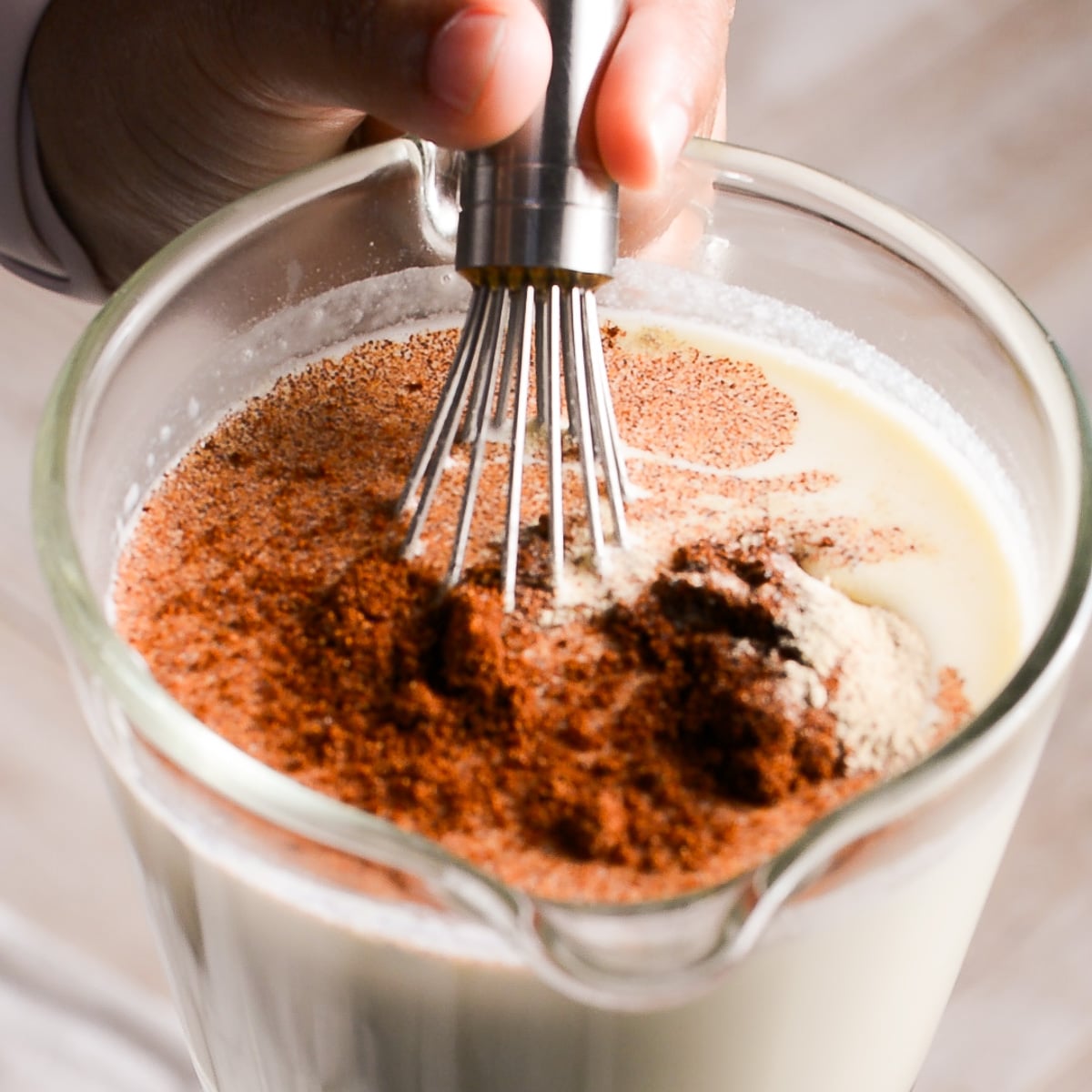 mixing milk, egg and seasoning together for custard mixture for an old-fashioned mac and cheese.