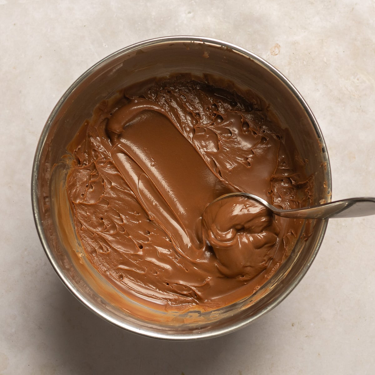 milk chocolate water ganache in a stainless steel bowl with a spoon.