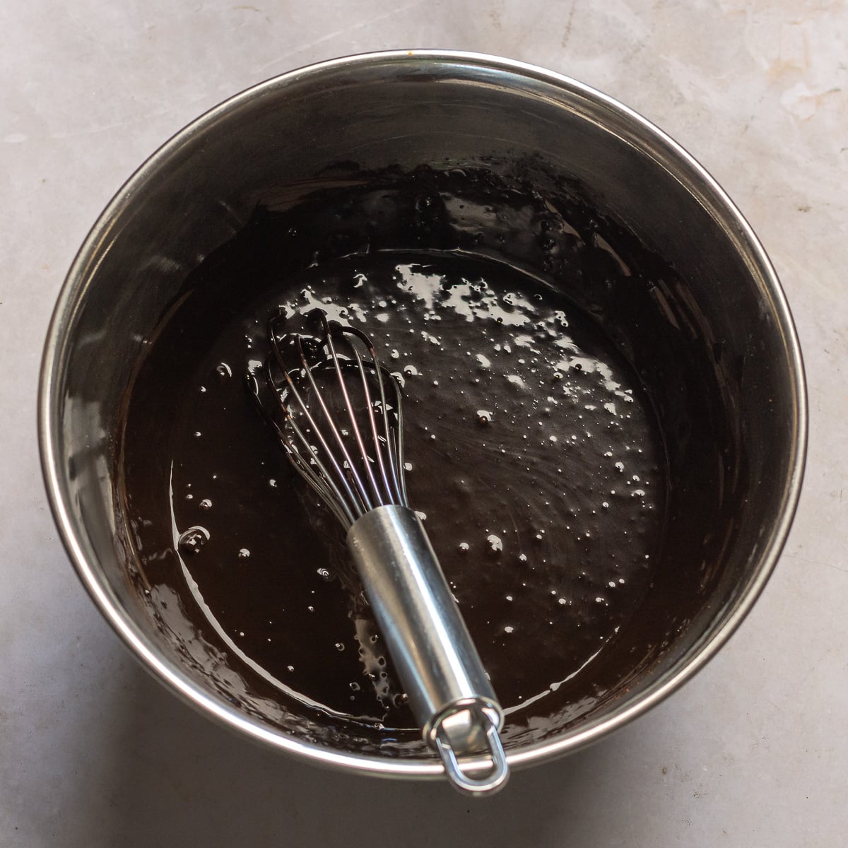 blooming cocoa powder with hot coffee and chocolate chips in a stainless steel bowl.