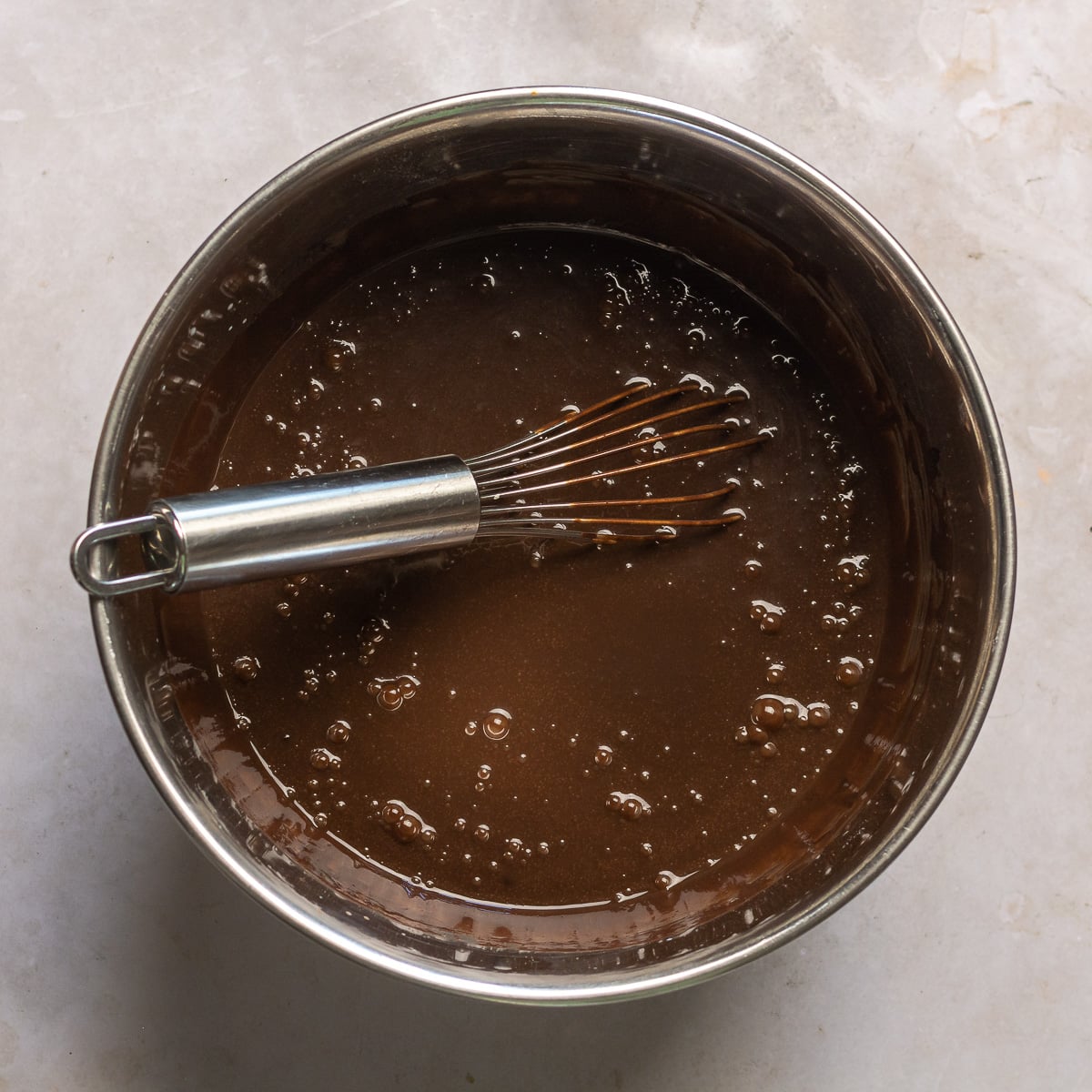 buttermilk added to bloomed cocoa powder in a stainless steel bowl.