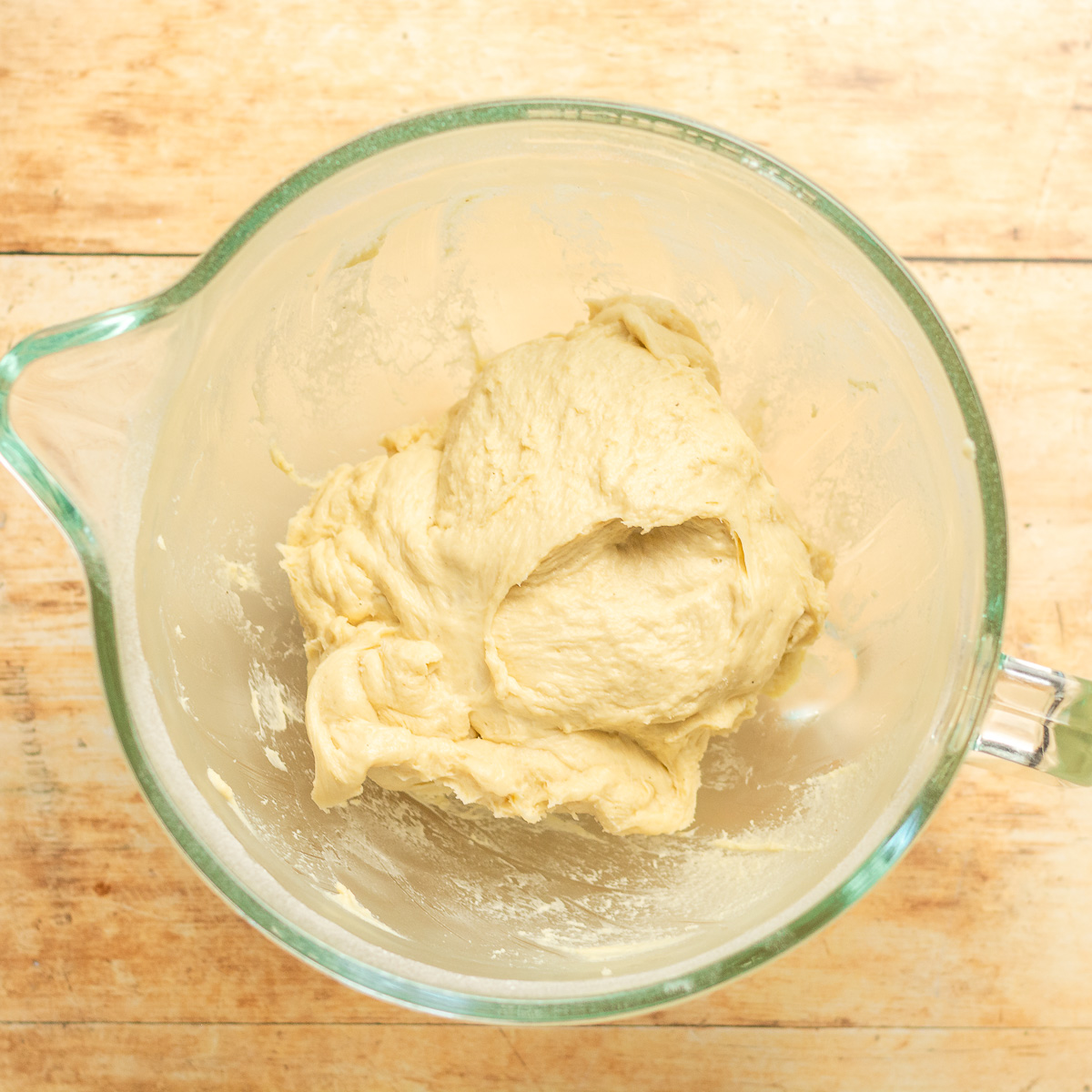 kneaded dough for homemade cinnamon buns in a glass bowl.