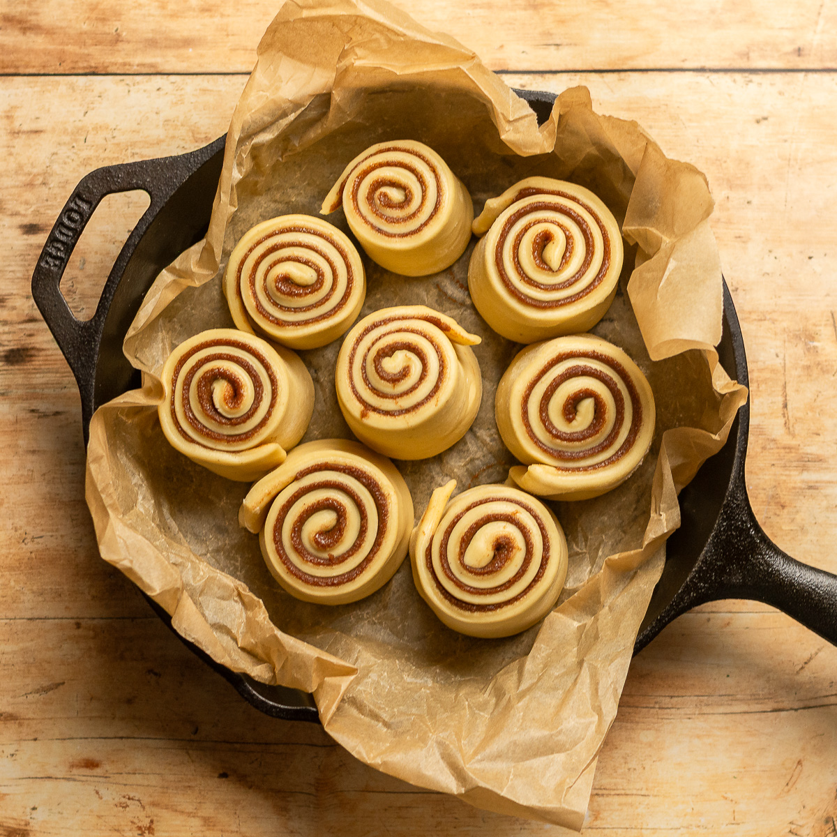 rolled cinnamon bun dough in a cast iron skillet.