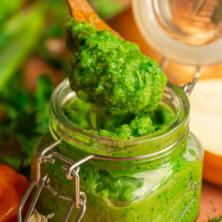 Jamaican green seasoning in a mason jar being scooped with a wooden spoon.