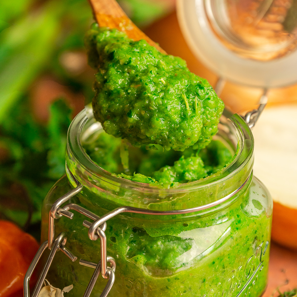 Jamaican green seasoning in a mason jar being scooped with a wooden spoon.