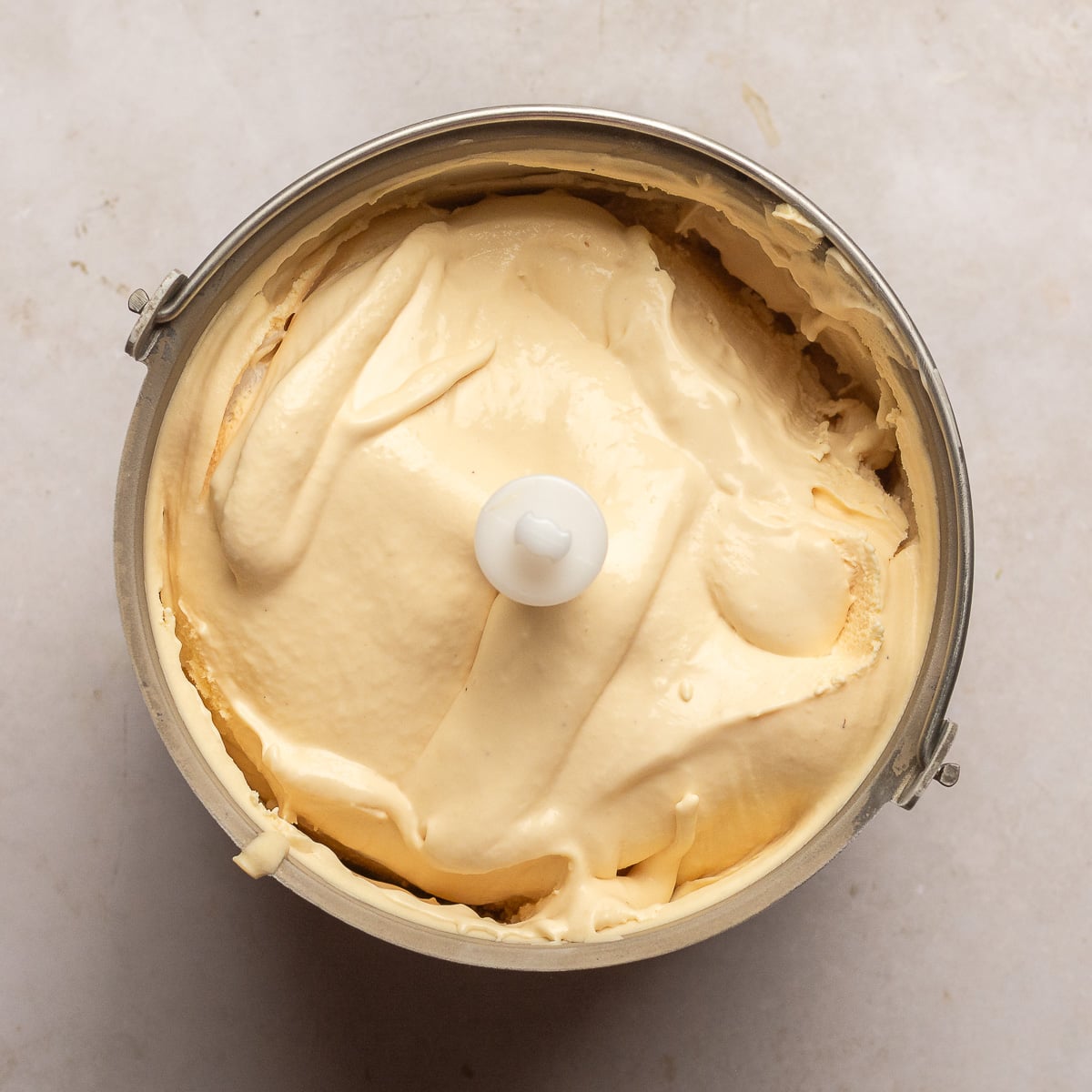 churned strawberry cheesecake ice cream in ice cream maker bucket.