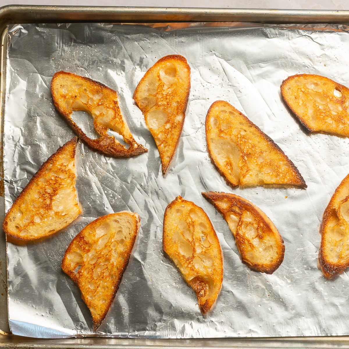 oven toasted crostinis on a foil-lined baking sheet.