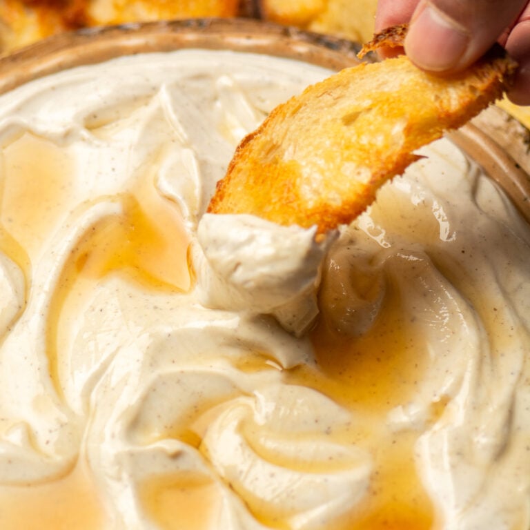 scooping up whipped ricotta with truffle and honey with a crostini.