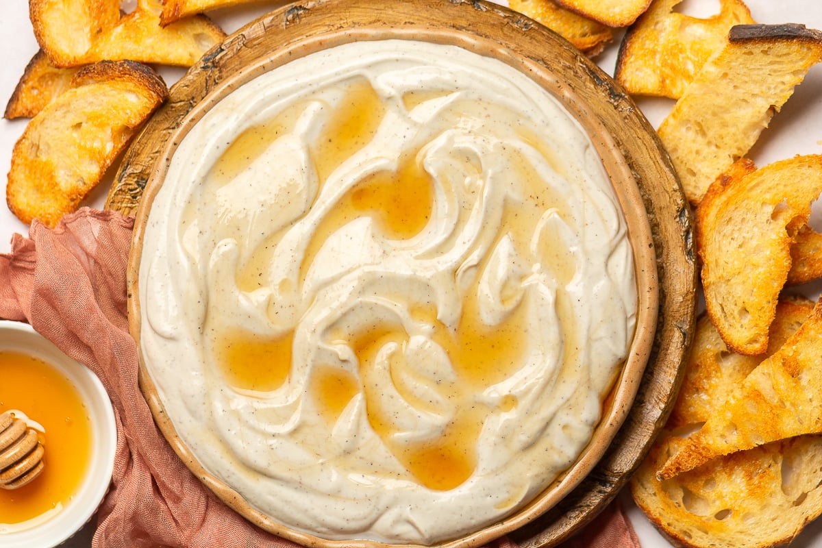 truffle and honey whipped ricotta in a plate surrounded by crostinis.
