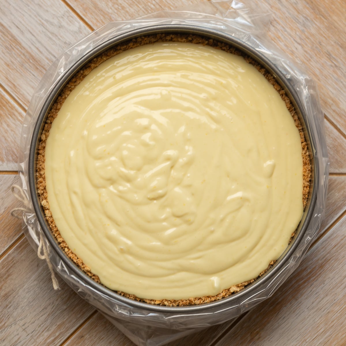 lemon cheesecake filling poured in a springform pan with a graham cracker crust.
