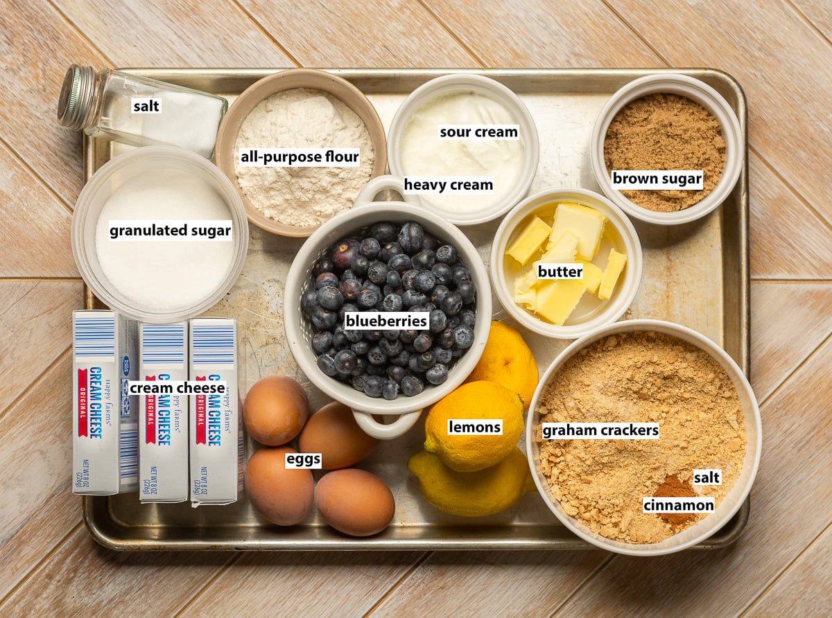 ingredients for lemon blueberry cheesecake crumble - lemons, blueberries, eggs, cream cheese, sugar, graham crackers, butter, cinnamon, salt, all-purpose flour, sour cream, heavy cream.