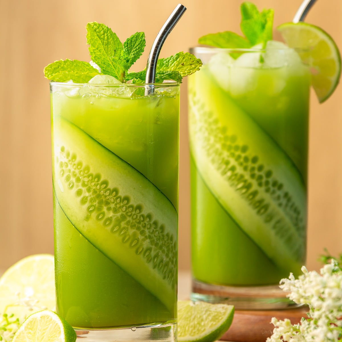 2 glasses of cucumber limeade garnished with a slice of cucumber and mint.