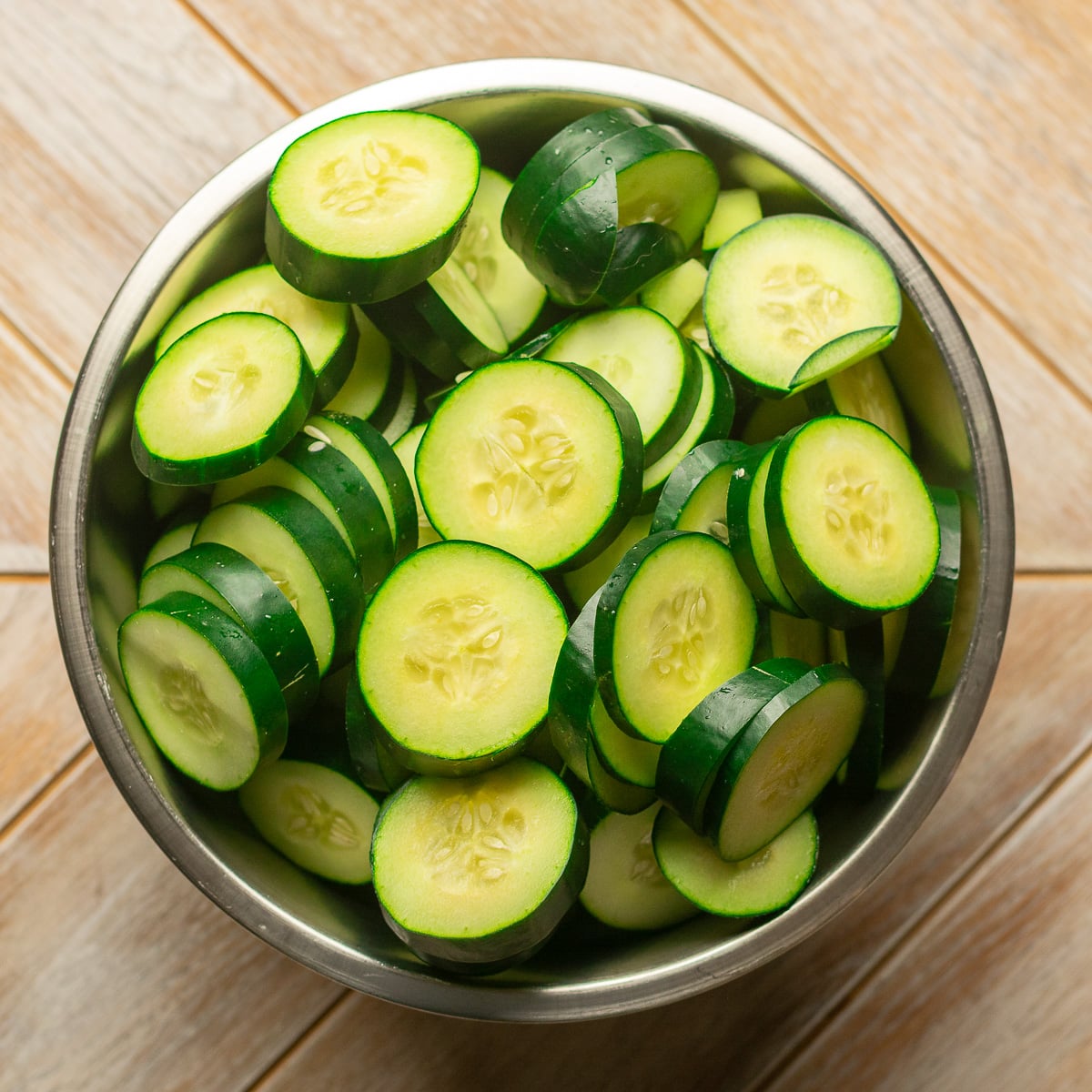 sliced cucumbers in a stainless steel bowl.