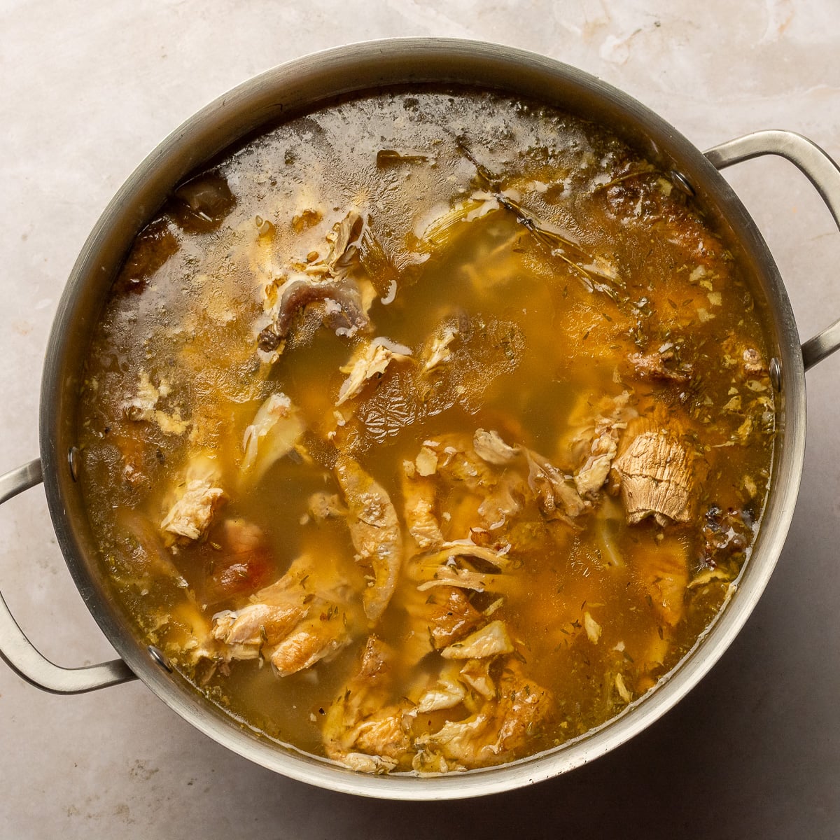 simmered chicken stock in a stainless steel stockpot.