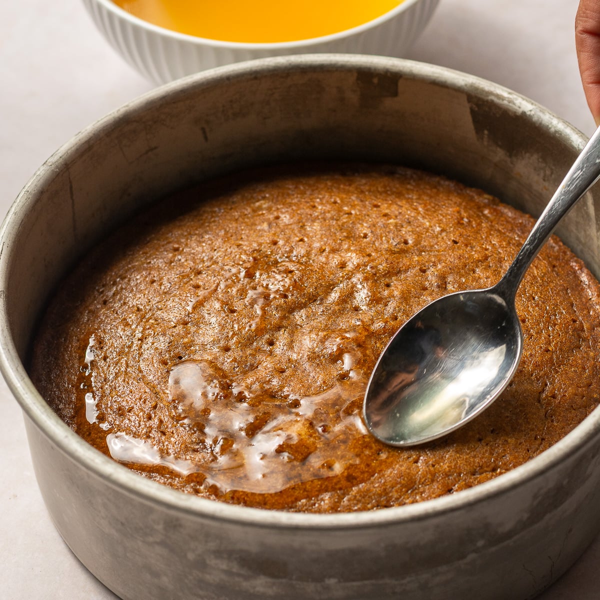spooning pineapple-rum simple syrup over hummingbird cake.
