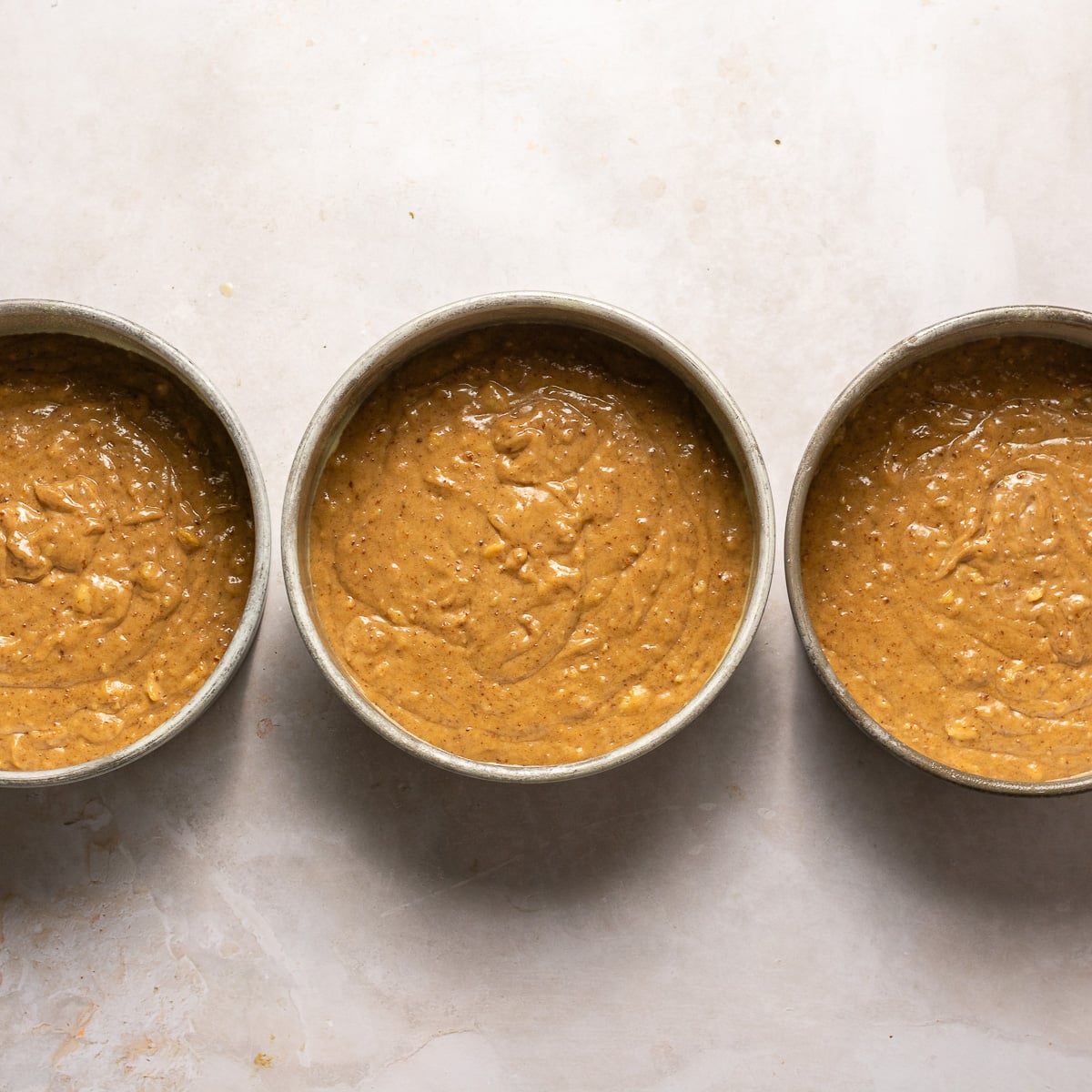 hummingbird cake batter in 3 eight-inch cake pans.