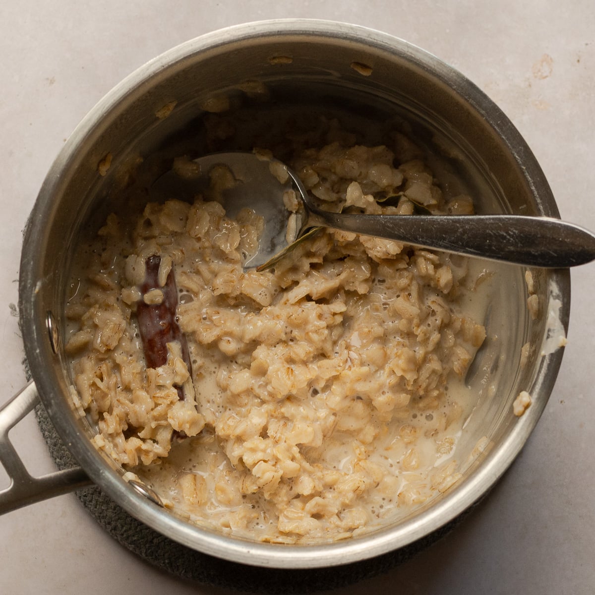 stovetop oatmeal in a stainless pot with bay leaf and cinnamon stick.