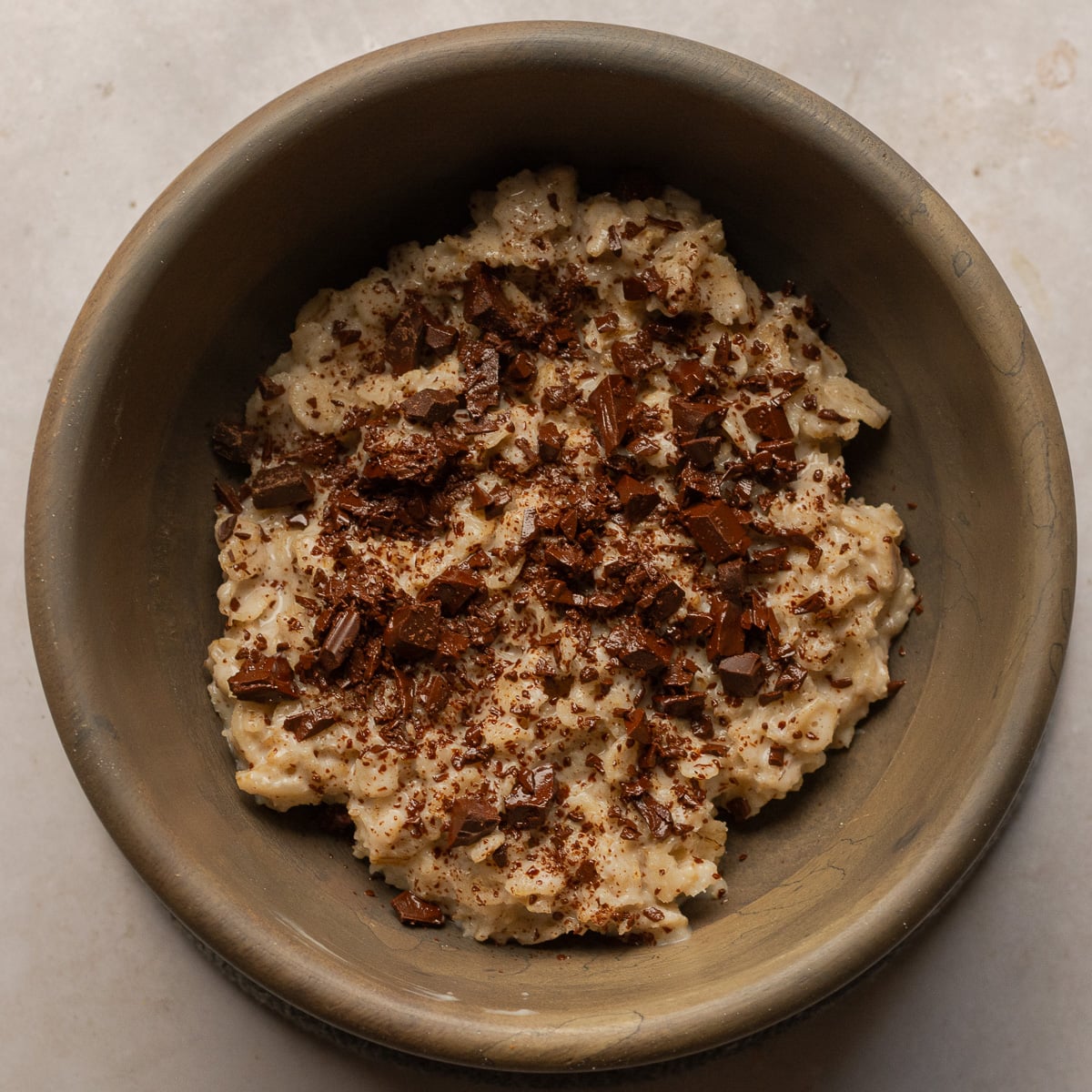 oatmeal topped with chopped semi-sweet chocolate in a wooden bowl.
