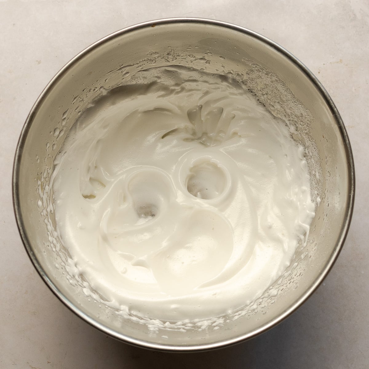 whipped meringue in a stainless steel bowl.